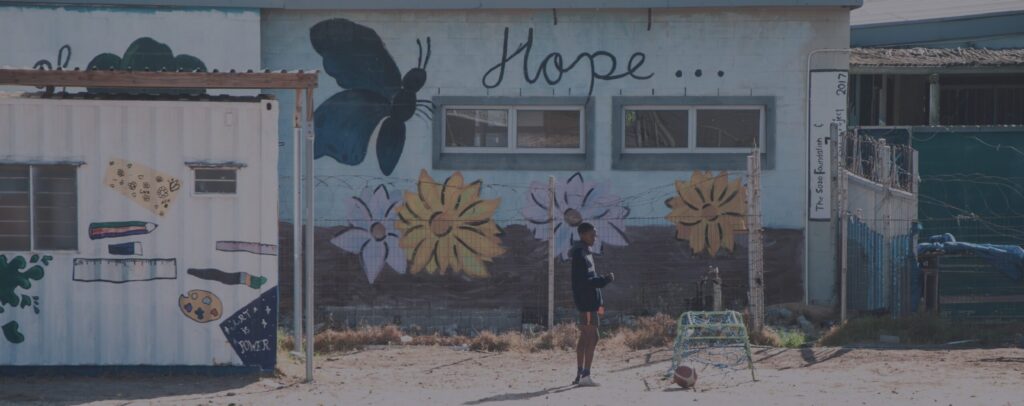 Boy with a football in front of the Sozo Foundation's 'Hope' mural building.