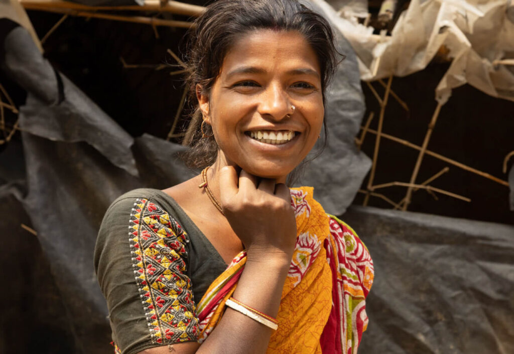 Smiling woman in a yellow sari standing outdoors in India.