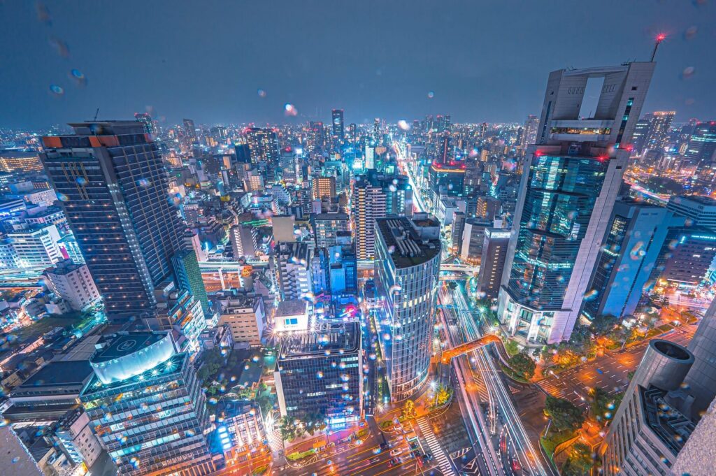 Aerial night view of a city with glowing skyscrapers and busy streets.